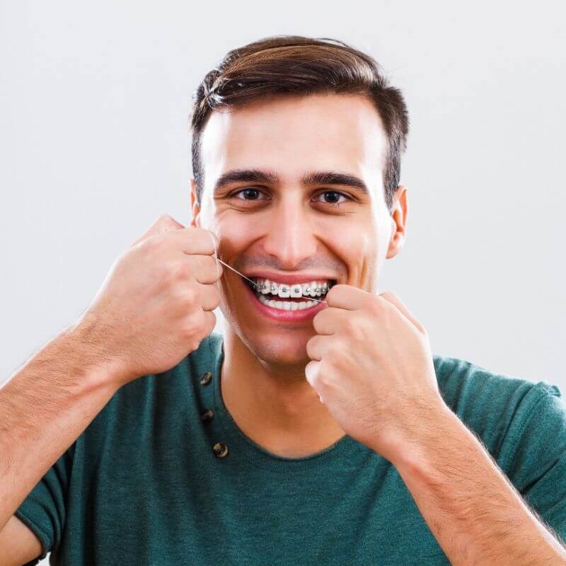 Man with braces and flossing